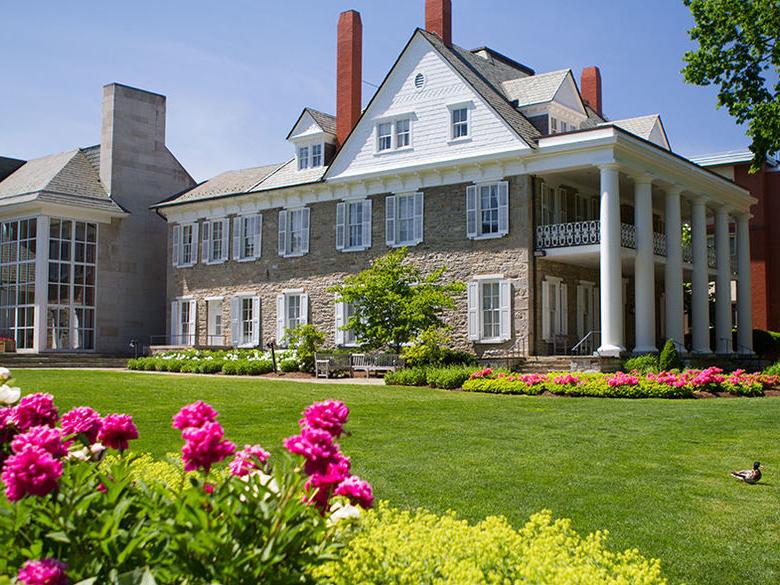 The well kept grounds at the Hintz Family 校友 Center at Penn State's University Park campus with flowers in the foreground an a mallard duck on the lawn