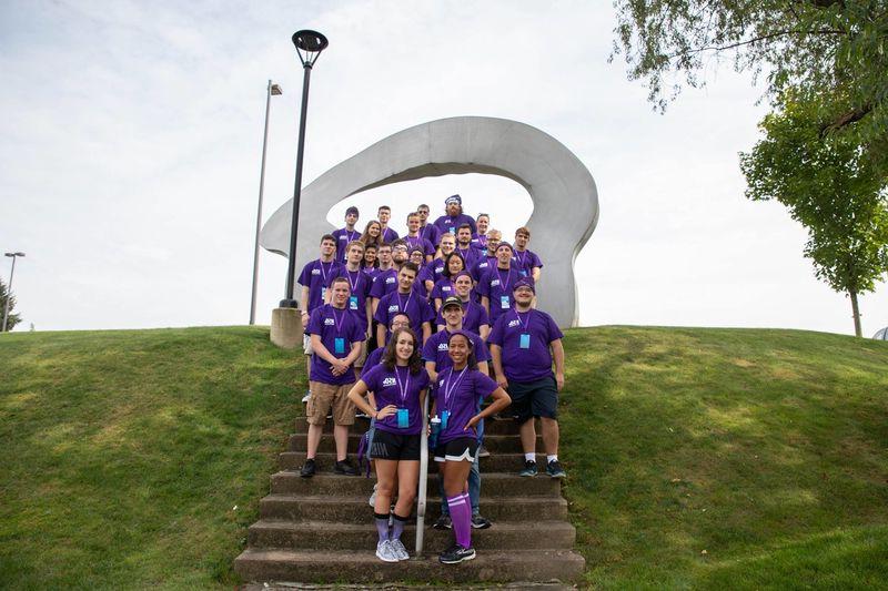 Students stand by Arch statue