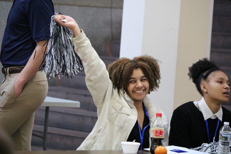 Student smiles and waves pom-pom