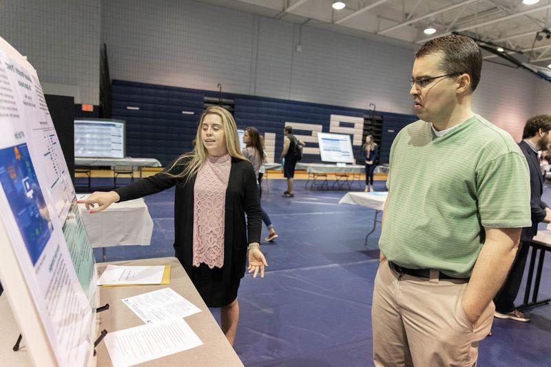 Female student points to poster board