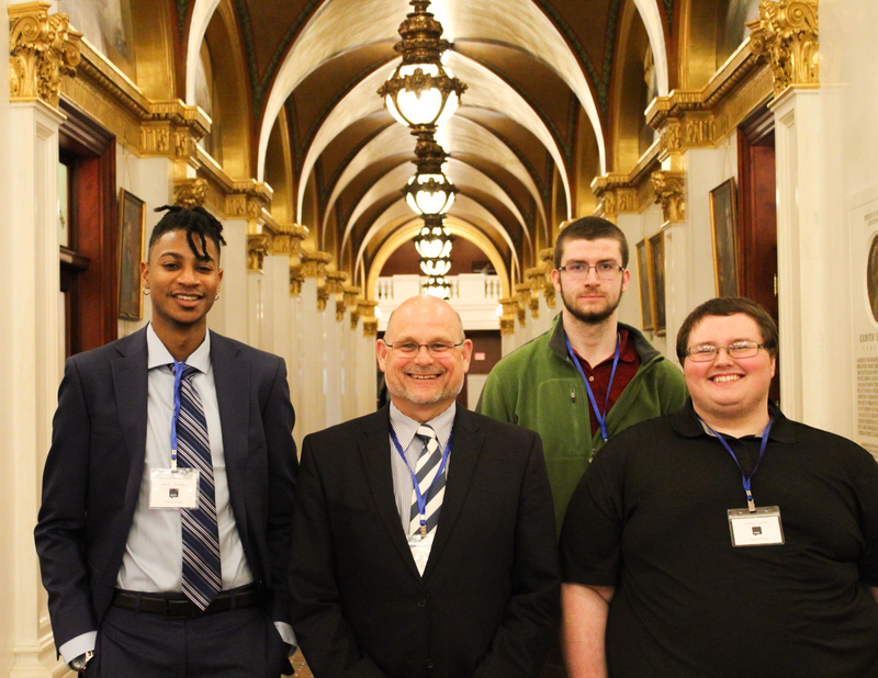 3 students and chancellor stand for photo