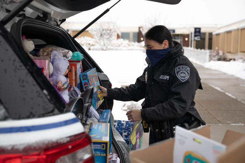 警察 officer loading police cruiser with donated items