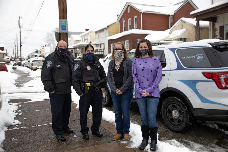 Four individuals stand outside wearing masks