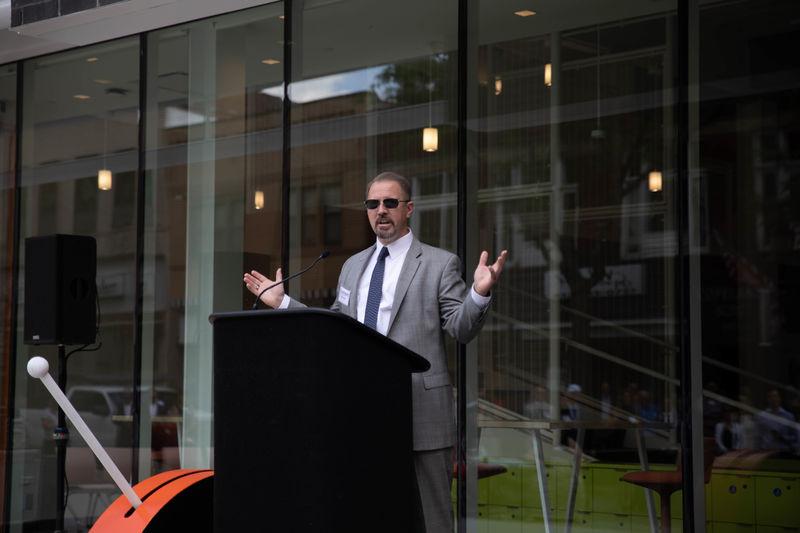 Man stands at podium with outstretched arms