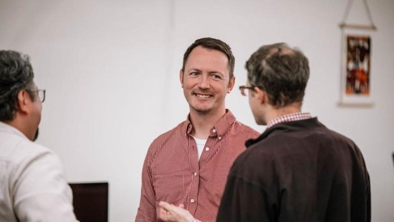 Man smiles as another man talks