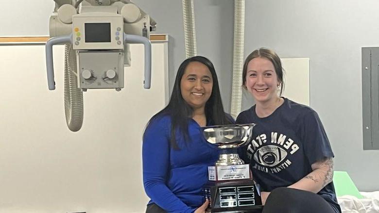 Two students hold trophy while smiling