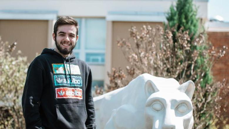 Student stands next to lion statue