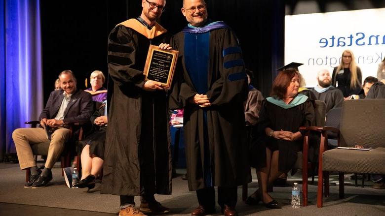 Two men stand on stage and smile for photo