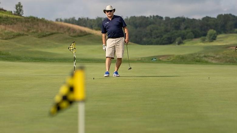 Man watches golf ball on green after putt