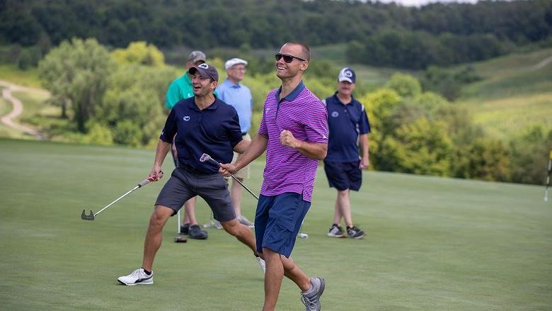 Man smiles holding golf putter