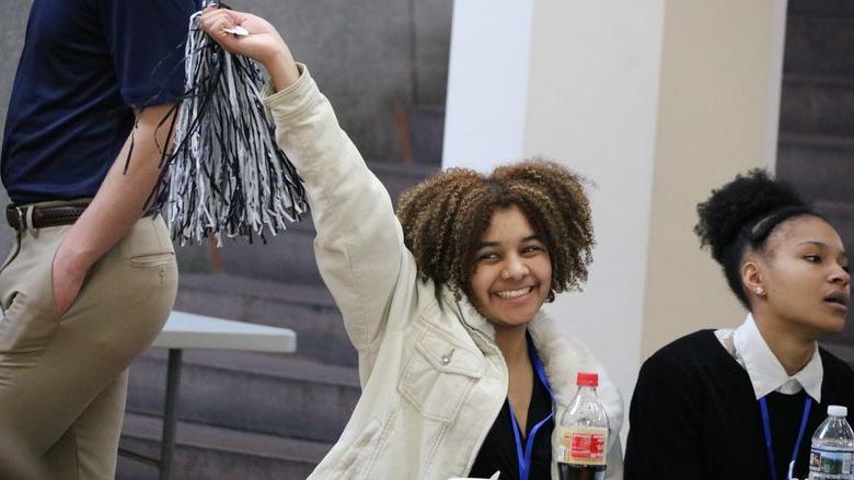 Student smiles and waves pom-pom