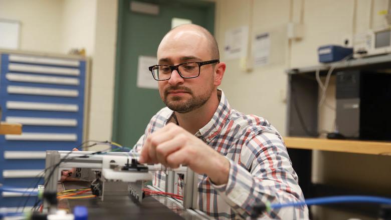 Joseph Cuiffi wiring conveyor belt in lab