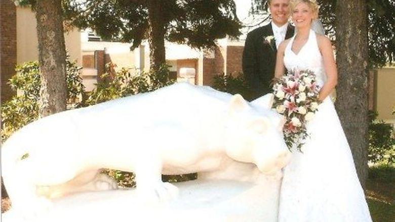 Bride and groom stand next to lion statue 