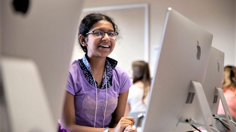 Female student sits by computers