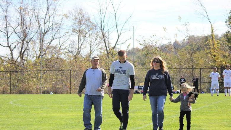 Four people walk across soccer field