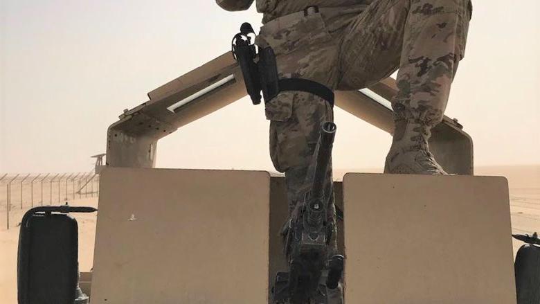 Man sits on M-ATV tank in desert holding Pittsburgh Terrible Towel