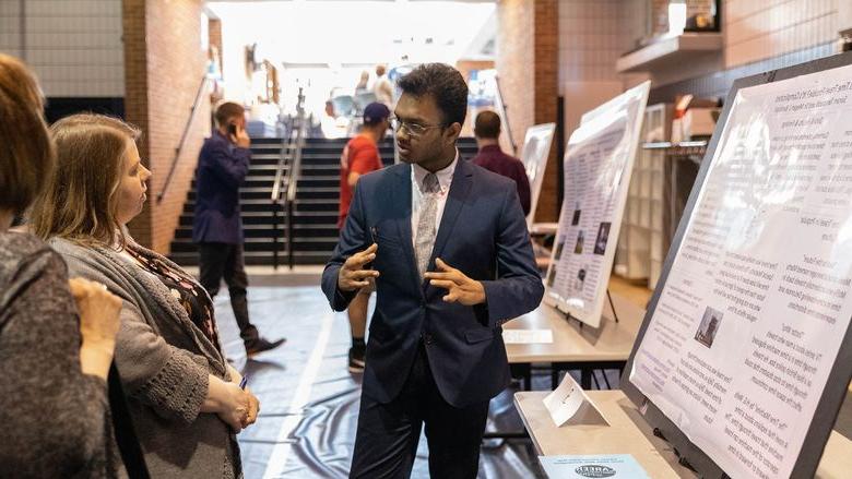 Male student presents research project to two females