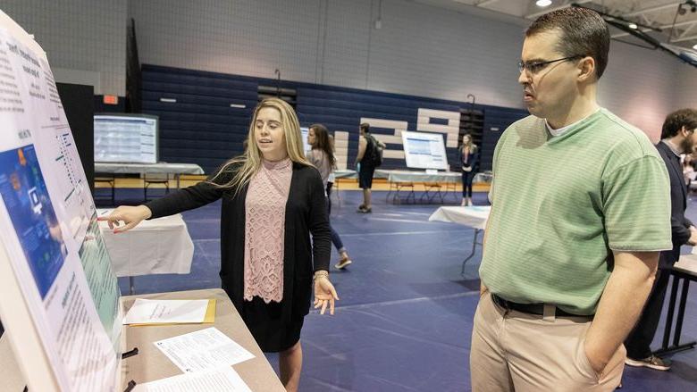 Female student points to poster board