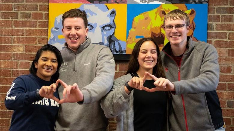 Four students stand and smile for photo