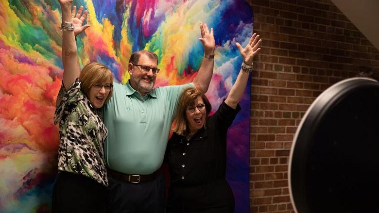 Two females and one male pose for photo at event