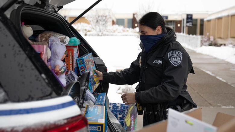 警察 officer loading police cruiser with donated items