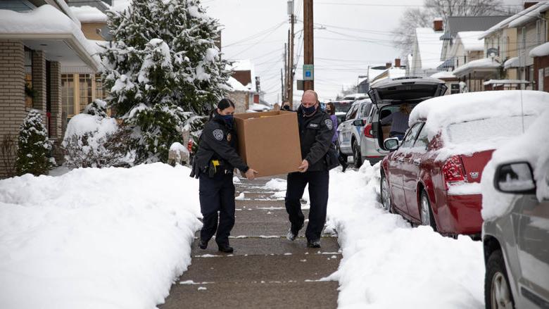 Two individuals carry box