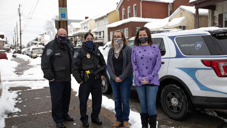 Four individuals stand outside wearing masks