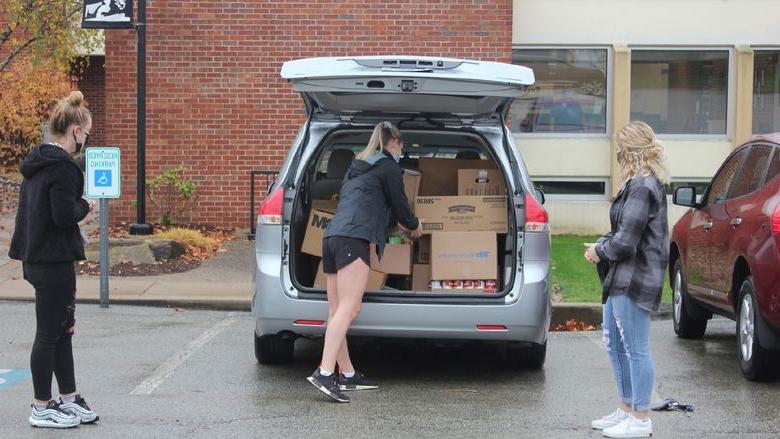 Student loads food donations into car