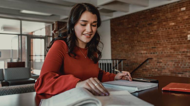 Student sitting at table with books and calculator