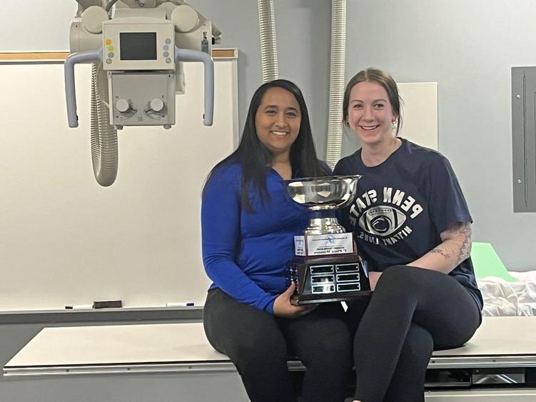 Two students hold trophy while smiling